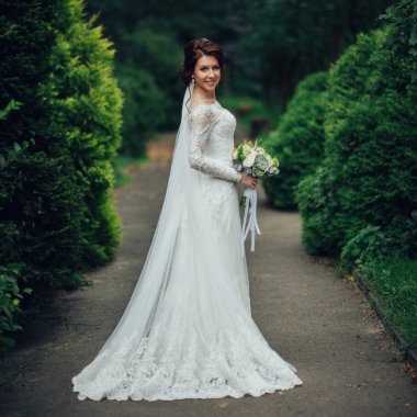 genç güzel gelin çiçeklerle parkta poz yan görünüm