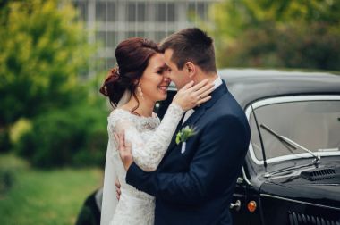 Retro arabanın önüne sarılma genç beyaz düğün çifti