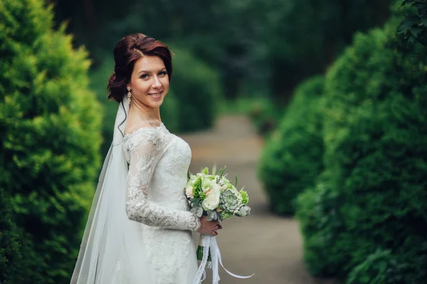 young attractive caucasian bride with flowers posing in park