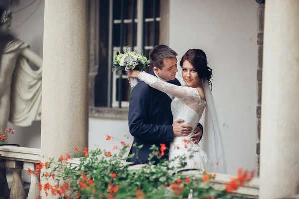 Genç beyaz düğün çift balkonda sarılma çiçek buketi ile