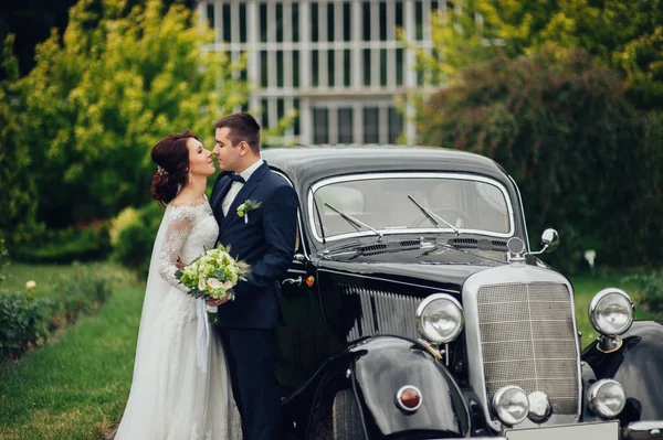 Kaukasische Bruidspaar Met Bloemen Boeket Knuffelen Naast Retro Auto — Stockfoto