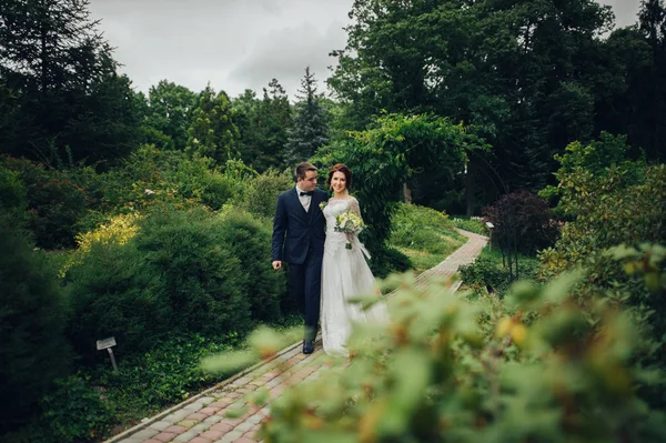 年轻迷人的白种人婚礼情侣花花束漫步在公园 — 图库照片