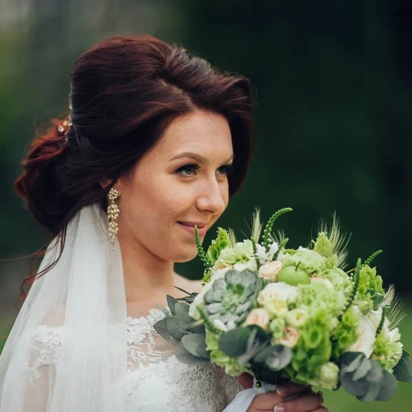 attractive caucasian bride with flowers posing in park