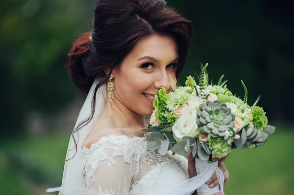 attractive caucasian bride with flowers posing in park