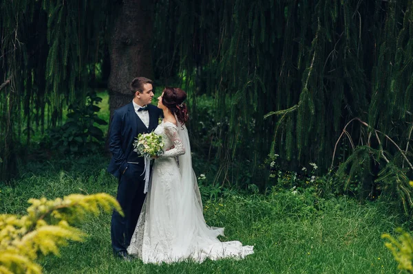 年轻美丽的新婚夫妇与鲜花花束拥抱在公园 — 图库照片