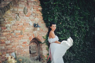 Romantik gelin yakınındaki eski tuğla duvar fener ile kamera poz 