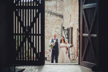 Yeni nikahlı çift gülümseyen ve eski binada poz