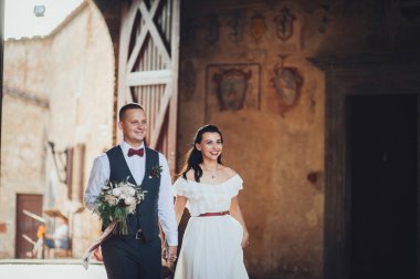 Yeni nikahlı çift gülümseyen ve eski binada poz