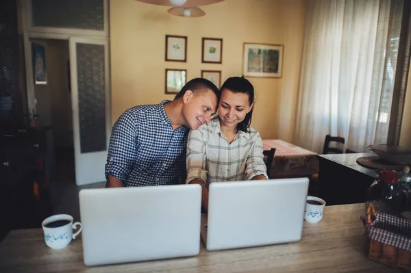 Young couple sitting in front of computers and making faces