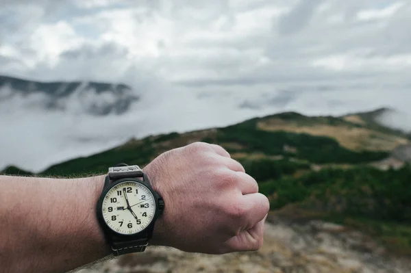 Male hand with watch with mountains on background