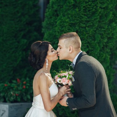 Yeni nikahlı çift parkta ağaçların arasında öpüşme