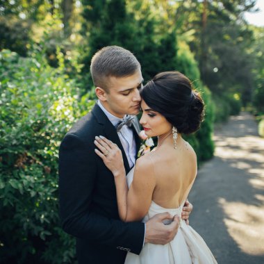 Gelin ve damat parkta ağaçların arasında sarılma