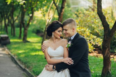 Yeni nikahlı çift parkta ağaçların arasında sarılma