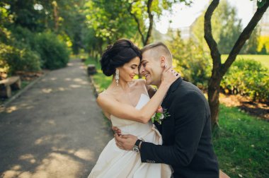 Yeni nikahlı çift parkta ağaçların arasında sarılma