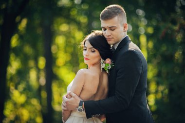 Yeni nikahlı çift parkta ağaçların arasında sarılma