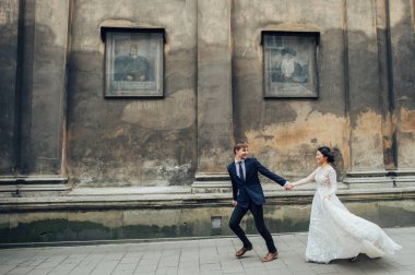 Eski ve perişan duvarı boyunca çalışan gelin ile damat