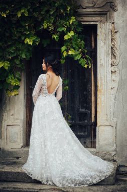 Yeşil ağaç dalları ile eski kapı karşı zarif gelinlik gelinin arkadan görünüm 