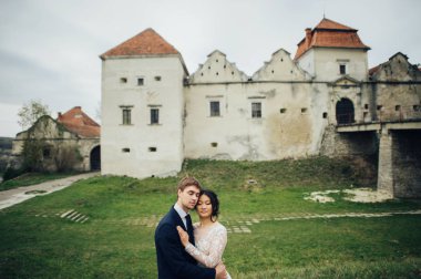 Yeni nikahlı çift ayakta eski kale önünde