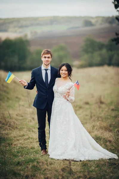 Brudgummen Och Bruden Poserar Med Flaggor Ukraina Och Taiwan — Stockfoto