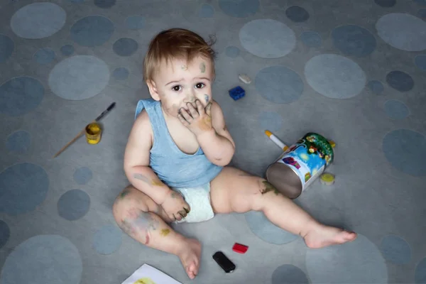 Aranyos kisfiú a padlón ül, és festés — Stock Fotó