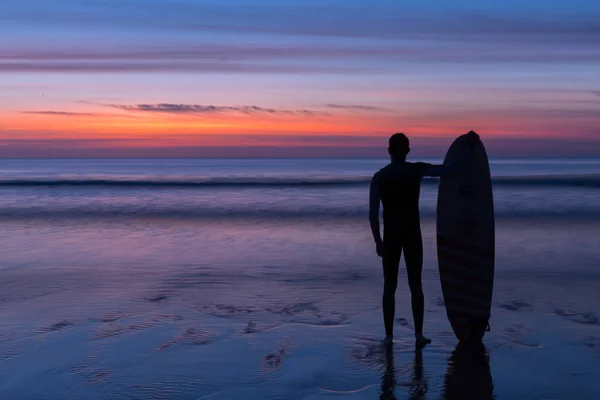 Surfista segurando prancha ao pôr do sol — Fotografia de Stock