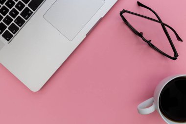 Dizüstü bilgisayar klavye kahve ve parlak pembe arka plan üzerindeki yükü gözlük okuma