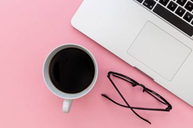 Dizüstü bilgisayar klavye kahve Kupası ve okuma gözlük parlak pembe bir arka plan üzerinde