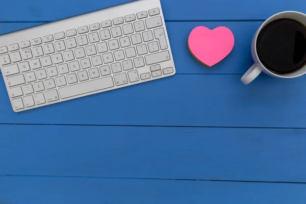 Wireless computer keyboard coffee and love heart on blue wood desk workspace