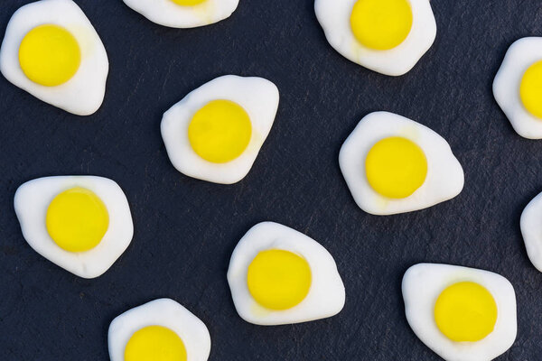 Fried eggs candy sweets overhead on dark background