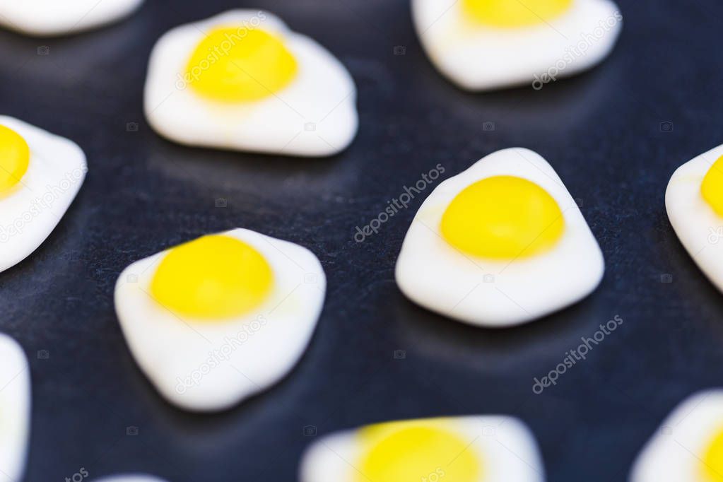 Fried eggs candy sweets closeup on dark background