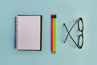 Eğitim defter kalem ve parlak mavi zemin üzerine gözlük
