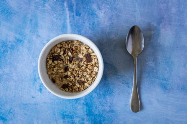 Kahvaltı gevreği kasesi, içinde meyve ve kaşık var.