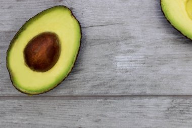 Avokado, arka planda en az vejetaryen sağlıklı gıdaya yarı yarıya bakar.
