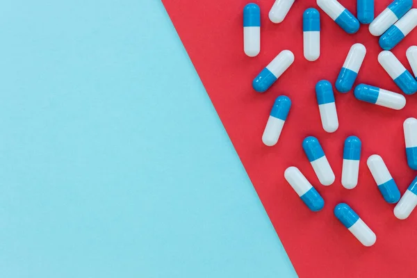 Drugs pills capsules on red blue background abstract top view me — Stock Photo, Image