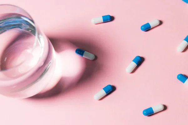 Стакан Воды Таблетки Капсулы Лекарствами Розовом Фоне — стоковое фото