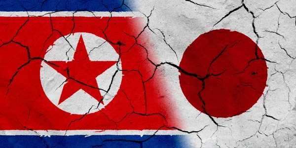 乾燥土壌テクスチャと北朝鮮と日本の旗 — ストック写真