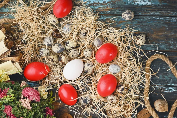 White chicken eggs, red eggs, quail eggs near dry flowers. Eggs For Easter.