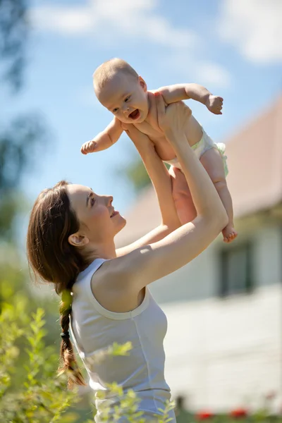 Happy woman holding in arm a baby outdoors — Stock Photo, Image