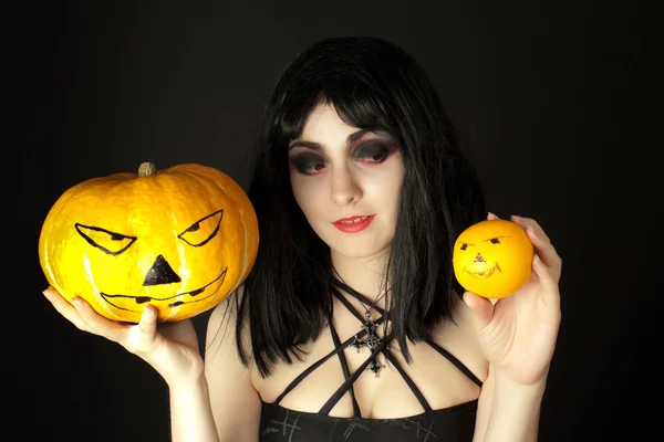 Mujer con maquillaje de Halloween sosteniendo una calabaza y una naranja —  Fotos de Stock