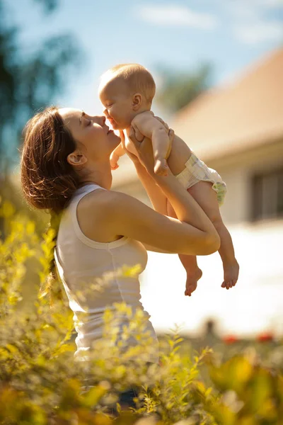 Happy woman holding in arm a baby outdoors — Stock Photo, Image