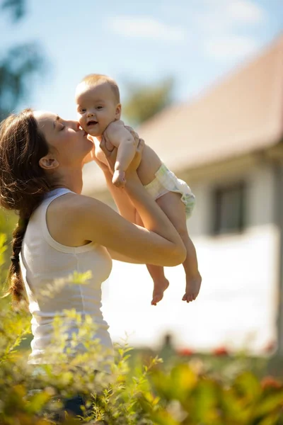 Happy woman holding in arm a baby outdoors — Stock Photo, Image