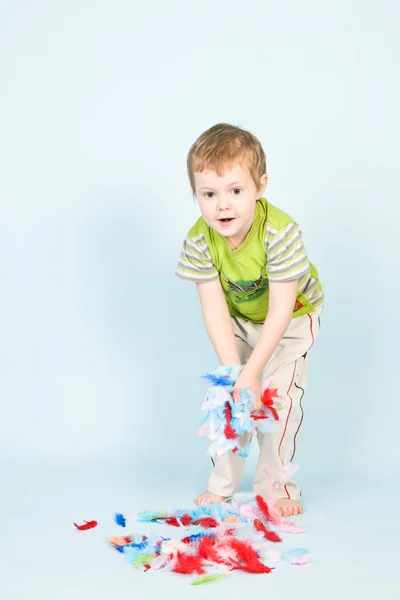 Boy playing with a lot of feathers — Stock Photo, Image
