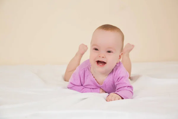 Фото очаровательного ребенка в фиолетовом телесном костюме лежащего на кровати — стоковое фото