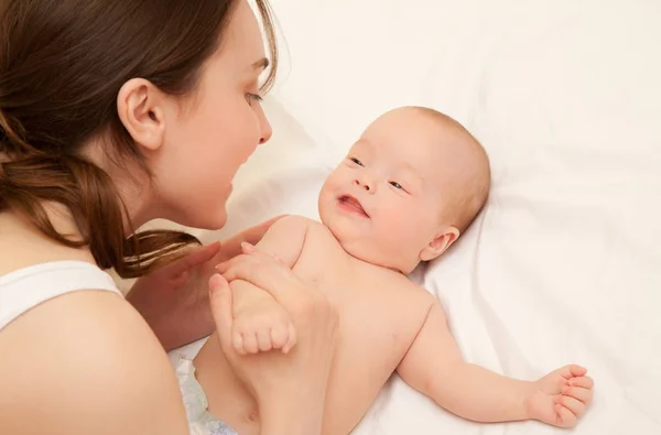 Foto de madre feliz con adorable bebé acostado en la cama — Foto de Stock