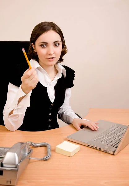 Young secretary with telephone, laptop and pencil thinking — Stock Photo, Image