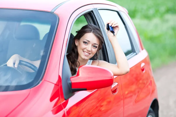 Glad kvinna i röd bil hålla knapparna och ler — Stockfoto