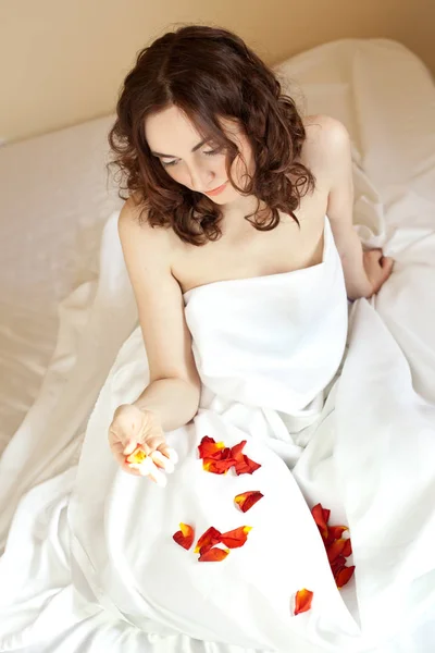 Piękna sexy kobieta trzymając płatki róż (punkt skupienia na ręce) — Zdjęcie stockowe