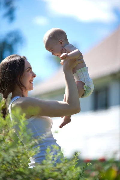Femme heureuse tenant dans le bras un bébé à l'extérieur — Photo