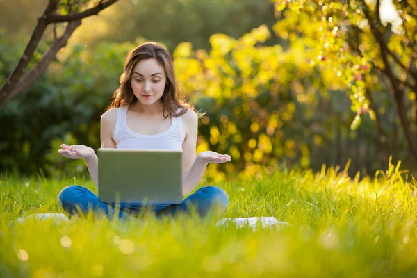 Kvinna med laptop i lotus pose arbetar på park — Stockfoto