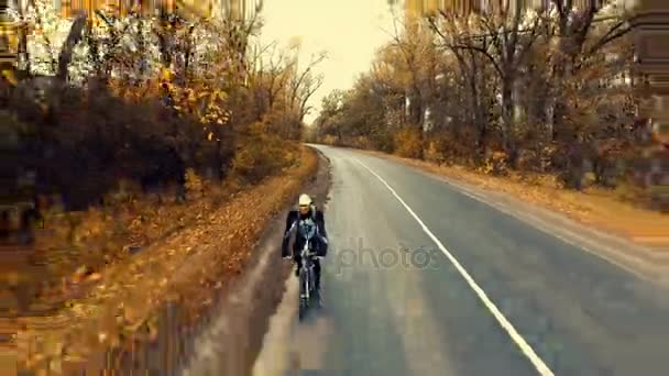 Kerékpár-ra egy út, egy festői őszi erdő a fiatal motoros — Stock videók